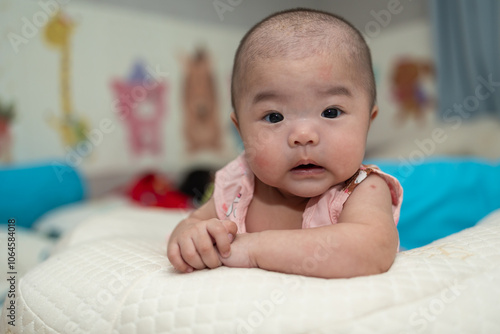 Happy Smiling face of 4 month old Asian Chinese baby girl during lying on bed. Happy Newborn child relaxing in bed