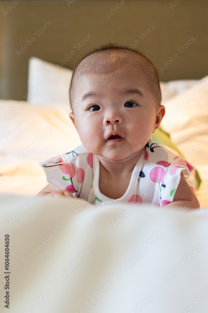 Adorable infant lying on a bed, surrounded by scattered red rose petals, displaying a joyful smile Adorable infant lying on a bed, surrounded by scattered red rose petals, displaying a joyful smile