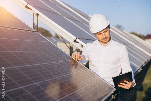 Engineer Inspecting Solar Panels With Digital Tablet Outdoors