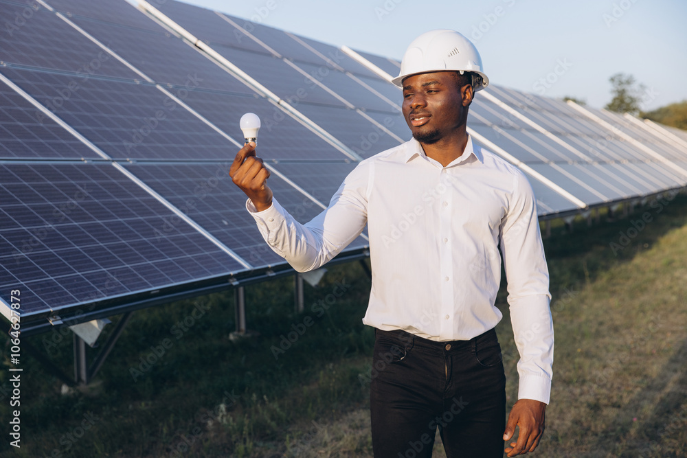 African American Engineer Examining Light Bulb Near Solar Panel Installation