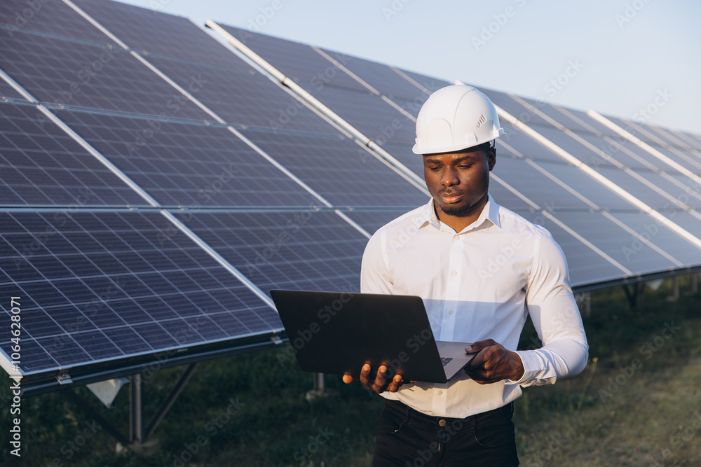 African American Engineer Inspecting Solar Panels in Field With Laptop African American Engineer Inspecting Solar Panels in Field With Laptop