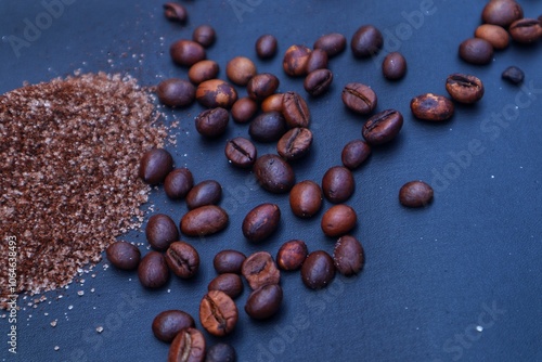 Instant coffee powder that has been mixed with granulated sugar, and coffee beans scattered around it on a dark background. With a close look. photo