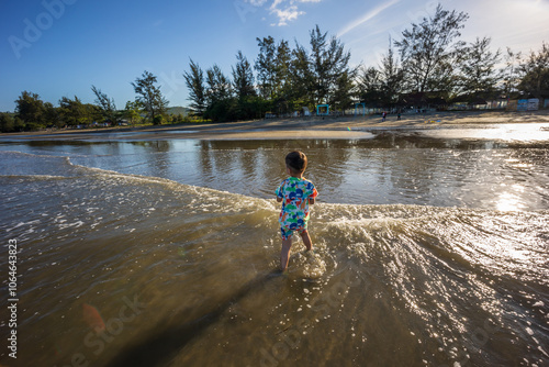 A joyful child plays in the sand at a sunlit beach, embodying the carefree spirit of summer and the joy of outdoor activities