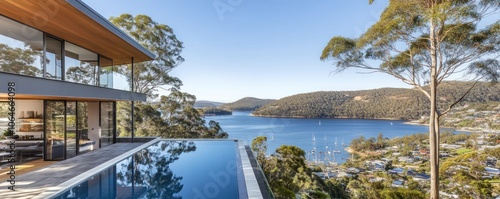 Modern home with pool overlooking serene bay and lush landscape.