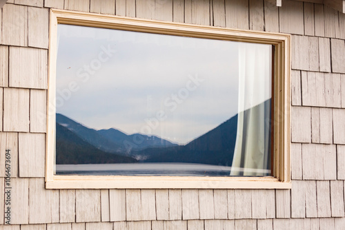 A cabin window reflecting a mountain landscape and the still waters of a lake.  photo