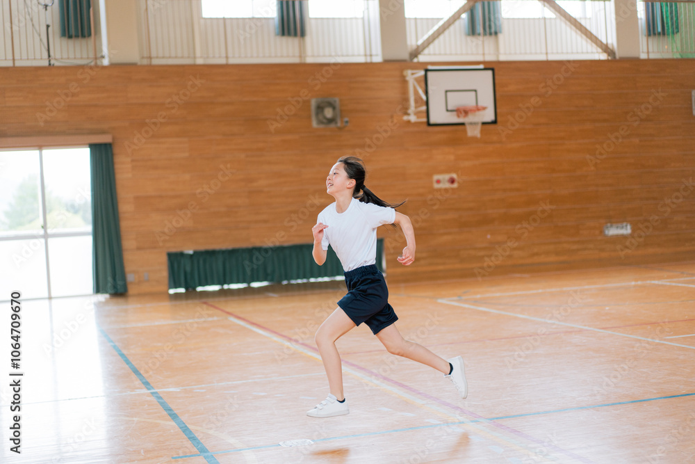 Fototapeta premium 学校の体育館の中で走る体操着姿の女子生徒