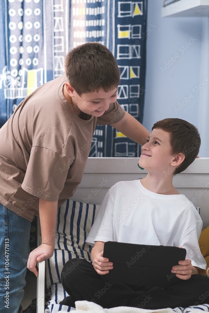 Fototapeta premium Boys enjoy various tablet activities together in a cozy bedroom, having a great time