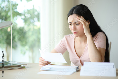 Worried asian woman complaining checking invoice at home