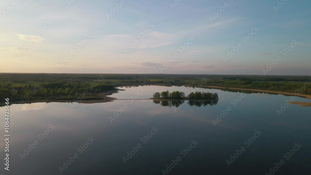 Drone flies right, smoothly orbiting a small island on a calm lake, drawing closer to it. Drone flies right, smoothly orbiting a small island on a calm lake, drawing closer to it.