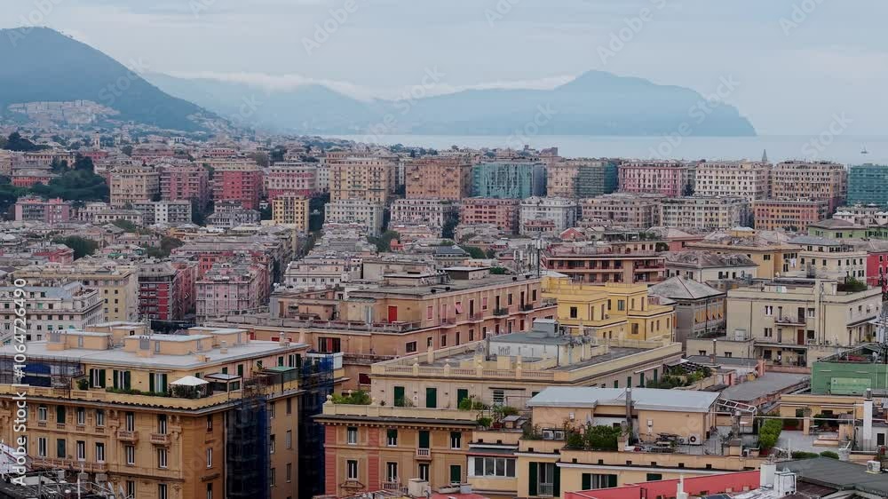 Overlooking colorful Genoa cityscape with distant mountains and coastal views under cloudy skies Overlooking colorful Genoa cityscape with distant mountains and coastal views under cloudy skies