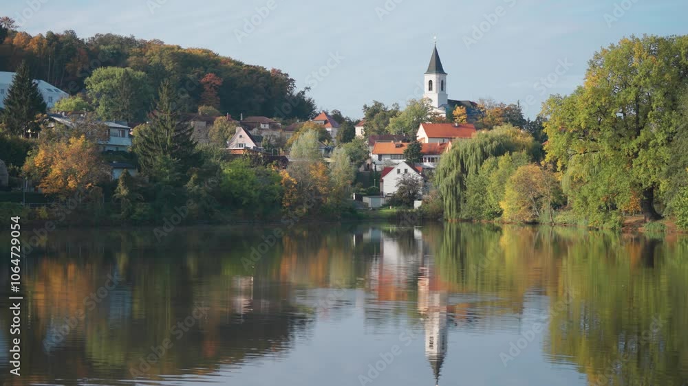St. Sebastian's and Fabian's Church in Prague stands above the lake surrounded by greenery and small tidy houses. St. Sebastian's and Fabian's Church in Prague stands above the lake surrounded by greenery and small tidy houses.