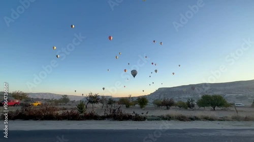 Hot air balloon atmosphere in Cappadocia, Türkiye, in blue clouds, surrounded by hills, captured using a handphone