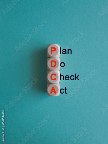 Wooden cubes with the orange words PDCA. It is an abbreviation for Plan, Do, Check, Act as eye-catching image. Beautiful blue background. Business concept.