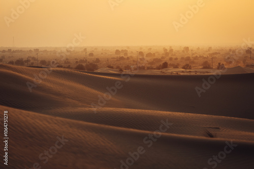 Views of the Dubai desert at sunset, footprints in the sand, with wind sweeping grains off the dunes.