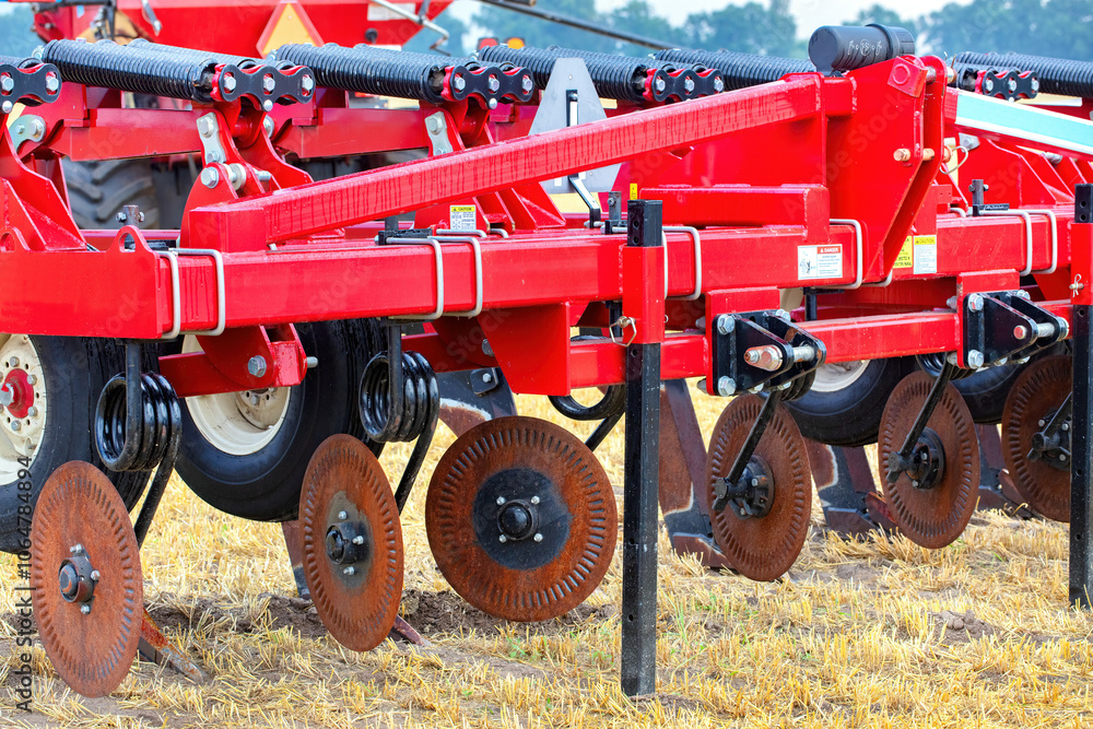 Agricultural machinery with red plow, close-up of farming equipment on field, steel disc harrows, rural farming concept