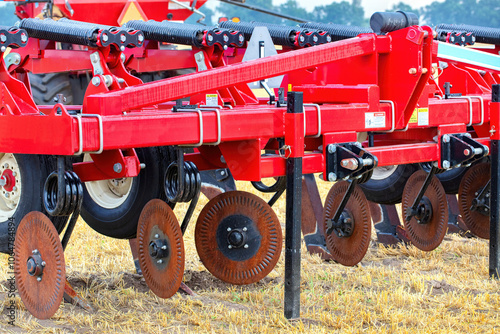 Obraz na płótnie Agricultural machinery with red plow, close-up of farming equipment on field, steel disc harrows, rural farming concept w salonie