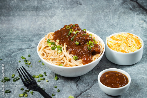 Kam heong chicken noodles with Spicy sauce, cabbage salad, green onion and fork served in bowl isolated on grey background side view of asian food photo