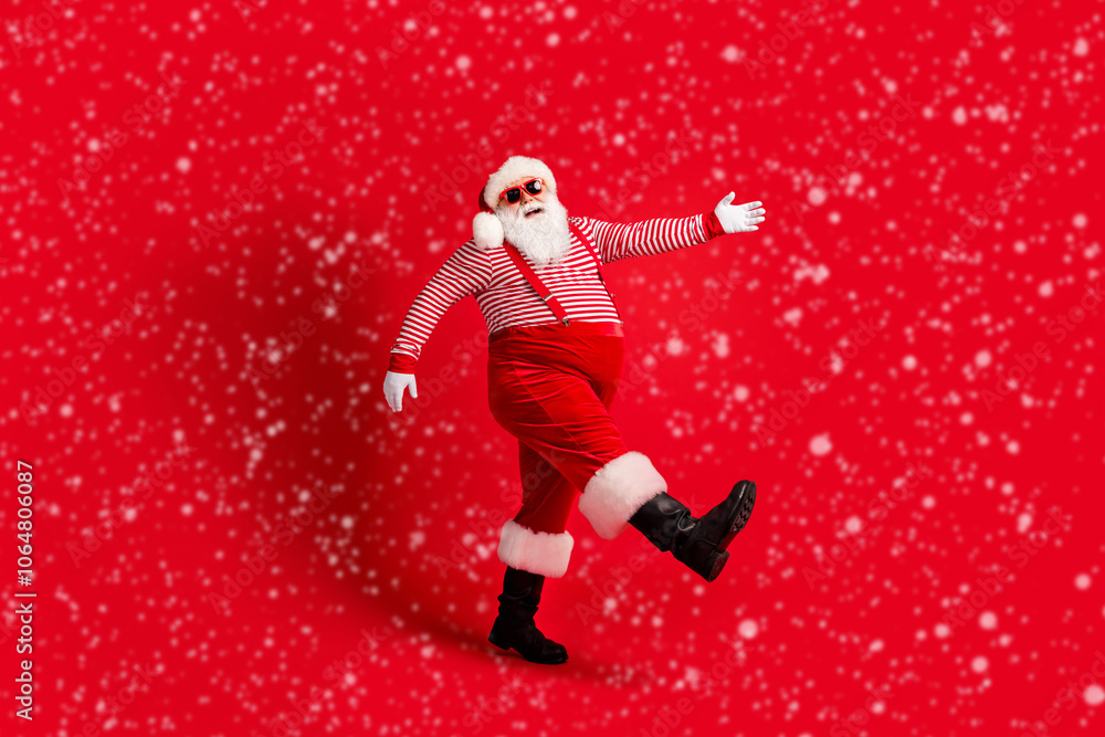 Full length photo of grandfather grey beard go look camera wear santa claus x-mas costume suspenders sunglass striped shirt cap boots isolated red color background Full length photo of grandfather grey beard go look camera wear santa claus x-mas costume suspenders sunglass striped shirt cap boots isolated red color background
