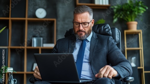 A business professional in a suit is seated in a stylish office chair, intently working on a laptop. The environment features modern decor and greenery, enhancing the workspace ambiance