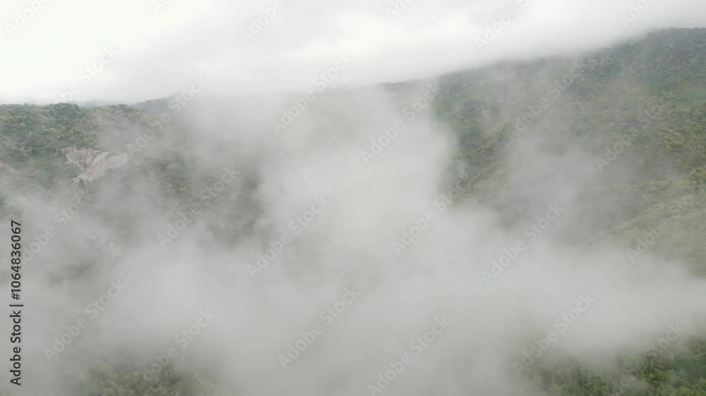 Dense fog settling over Zagori mountains, aerial overview of moody, misty landscape in Greece, descend and enter into clouds to reveal lush greenery Dense fog settling over Zagori mountains, aerial overview of moody, misty landscape in Greece, descend and enter into clouds to reveal lush greenery