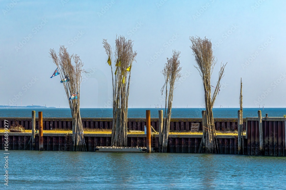 The pricks or bars mark a narrow and flat fairway. Pricken or poles are used as permanent navigation marks where buoyancy would be too expensive or not possible because the water depth is too shallow