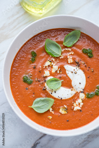 Soup made of roasted tomatoes and red bell peppers with addition of cream and cheese, vertical shot, middle close-up, elevated view