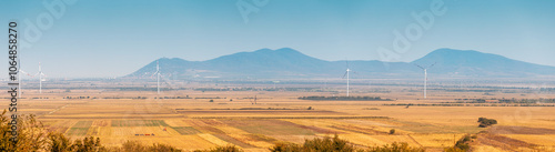 Scenic landscape of Vrsac, Serbia, featuring majestic mountains and a picturesque farm with wind turbines harnessing renewable energy photo