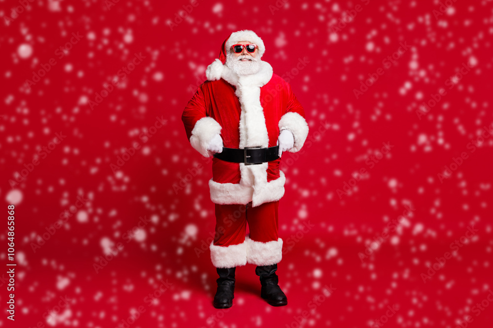 Fototapeta premium Full length photo of retired old man grey beard self-assured hands hips christmas tree event wear santa costume gloves coat belt sunglass headwear black boots isolated red color background