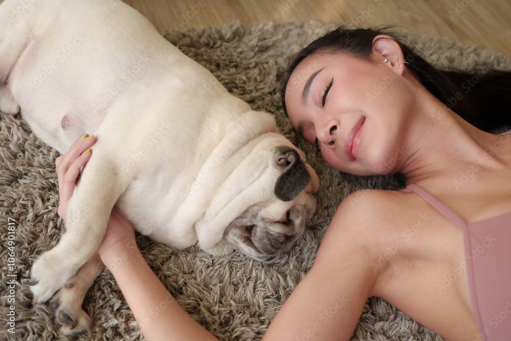 Pretty Young Asian woman lying closely with pug dog on rug, eyes closed in peaceful moment of affection and connection and calm expressions. Pretty Young Asian woman lying closely with pug dog on rug, eyes closed in peaceful moment of affection and connection and calm expressions.