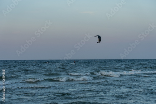 People swim on the sea on a kiteboard or kitesurfing. Kitesurfing lessons on the bay. Summer sport learning how to kitesurf. Kite surfing on bay. Hel Peninsula,Puck bay, Jastarnia, Poland.