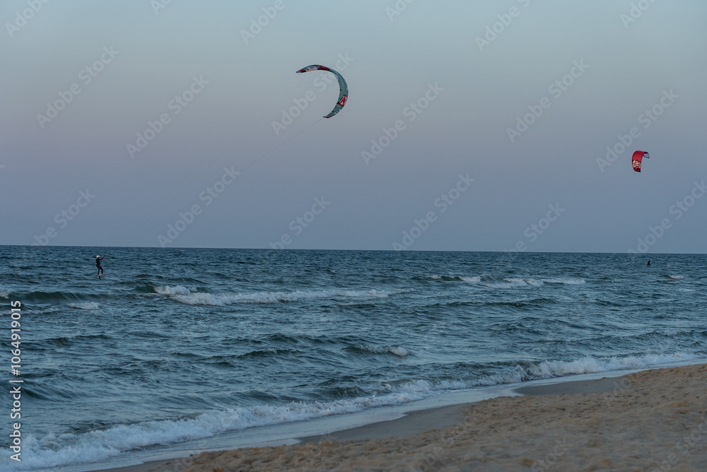 People swim on the sea on a kiteboard or kitesurfing. Kitesurfing lessons on the bay. Summer sport learning how to kitesurf. Kite surfing on bay. Hel Peninsula,Puck bay, Jastarnia, Poland. People swim on the sea on a kiteboard or kitesurfing. Kitesurfing lessons on the bay. Summer sport learning how to kitesurf. Kite surfing on bay. Hel Peninsula,Puck bay, Jastarnia, Poland.
