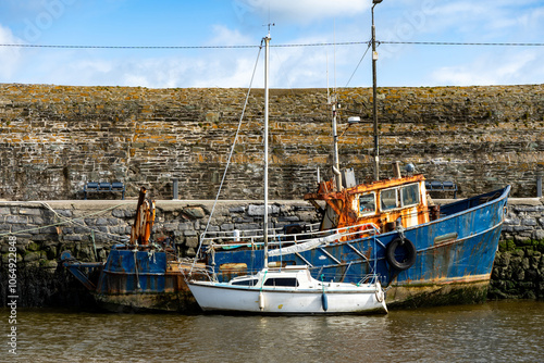 Sea dock with old rusty fishing boats and brick wall photo