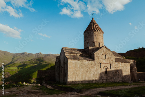 Tatev Monastery perched on a hillside with stunning mountain backdrop during golden hour