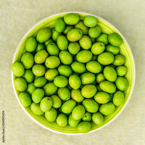 plate with fresh green olives on monochrome green salad background. Olive dish closeup, foor and drink concept photo