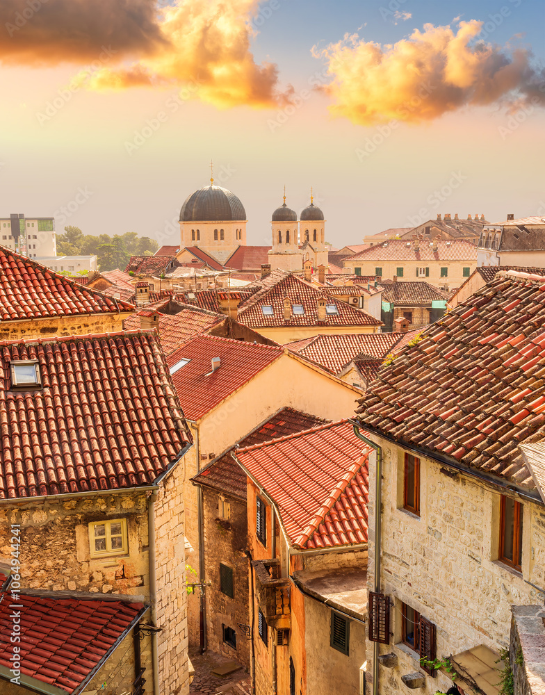 Obraz premium beautiful old city sunset landscape with ren and orange tile roofs of houses and nice cathedral church in traditional venetian style with bell tower and chapel and evening sky on background