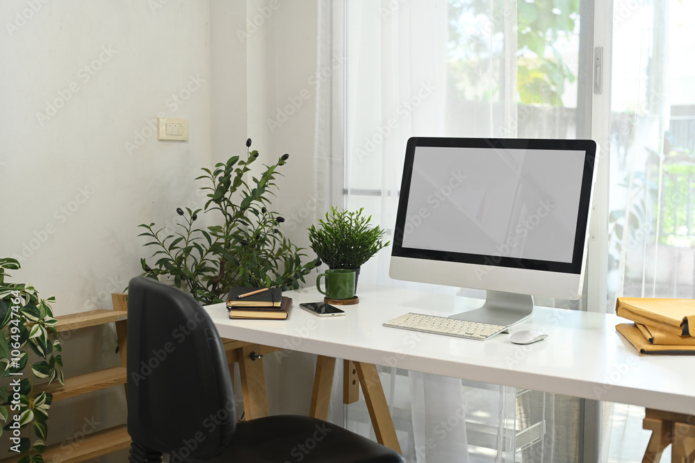 Obraz premium Contemporary workspace with a white computer monitor, plants and natural light