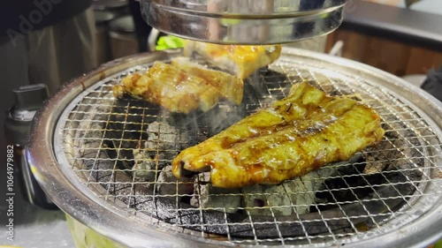 An employee at a Korean barbecue restaurant grills fresh eels over charcoal