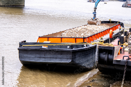 A Large Barge Boat Being Loaded With Rocks And Debris From The Edge Of The River Thames photo