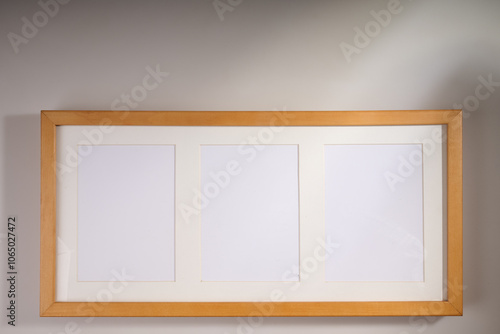 Wooden frame for three pictures on white wall with light and shadows