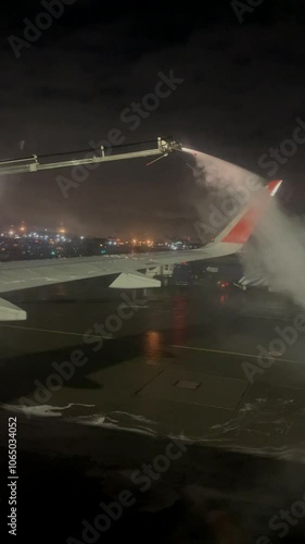 A technician treats an airplane wing with deicer before a flight. photo