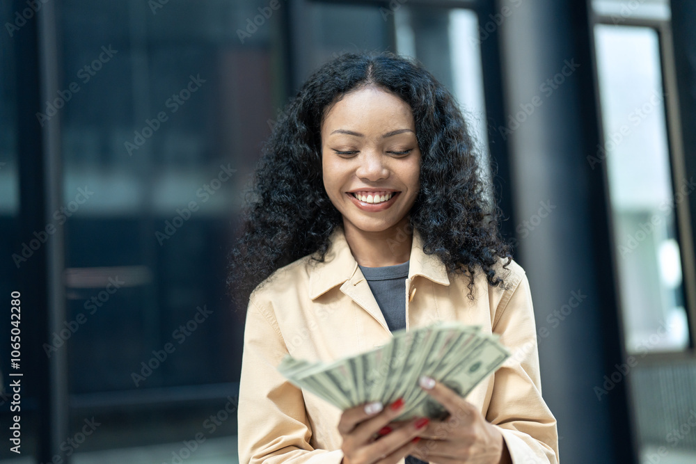 Cheerful young woman holding and counting a stack of cash in an outdoor setting, representing financial success and happiness. Cheerful young woman holding and counting a stack of cash in an outdoor setting, representing financial success and happiness.