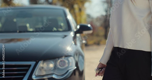 Man hand gives a car keys to woman hand in the car dealership close up. Unrecognized auto seller and a woman who bought a vehicle. Dealer giving key to new owner in auto show or salon. photo