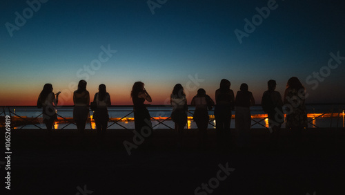 Young people talking and watching the sunset over the sea