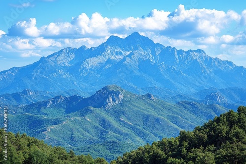 Majestic mountain peaks rising above lush green valleys under a cloudy blue sky photo