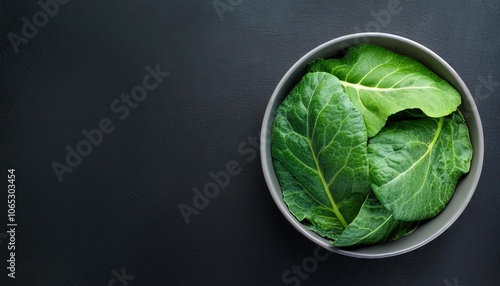 Collard green in a bowl on a black background, top view, copy space photo