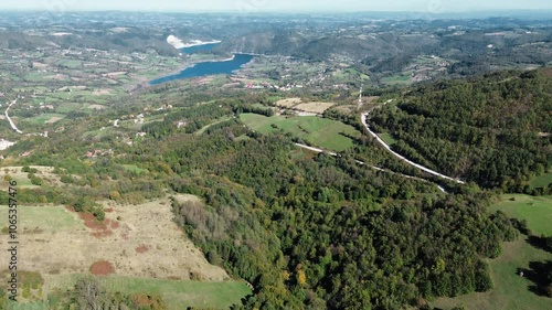 An asphalt car road runs through the green fields and forests of western Serbia in early autumn. Aerial view from drone shot. Beautiful breathtaking landscape of eastern Europe photo