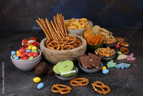 Salty and sweet snacks. Pretzels, chips, crackers, popcorn in wooden bowls on table