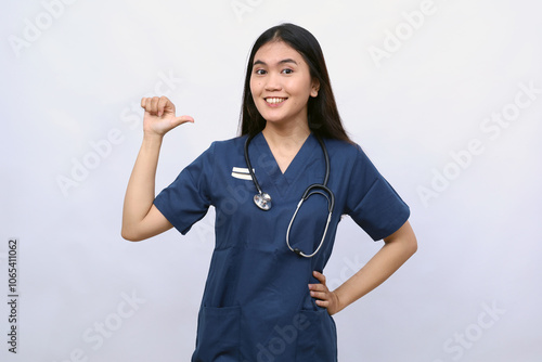 Professional confident female asian doctor, nurse in scrubs pointing at herself and smiling, guarantee she knows what do, white background photo