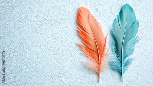 Two vibrant feathers in a beautiful combination of coral and teal stand out against a light blue textured background, adding a touch of whimsy to any project. photo