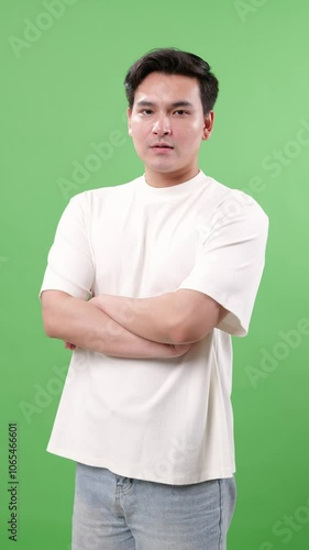 Confident Asian young man with arms crossed, looking directly at the camera with a calm, assured expression. Ideal for themes of confidence, leadership, and trustworthiness, Vertical 4K Video